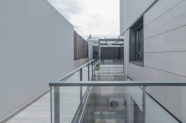 Modern ışıklı koridor, sertleştirilmiş cam parmaklıklar ve parlak gümüş kutsanmış alüminyum yapı.