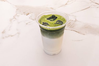 Soğuk neşe üçlüsü: Baharatlı Ice Chai Latte, canlı Matcha Latte, ve klasik Latte, akşam ışığında bir masada birlikte.