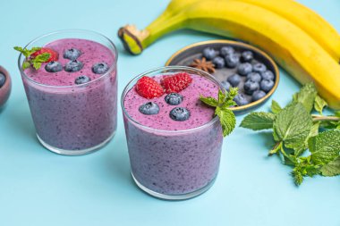 Kahvaltıyı canlandırmak: yabanmersini ve ıspanaklı smoothie bir kase taze böğürtlenin yanında, doğal ortamında.