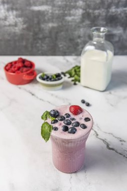 Doğal Yabanmersini Gazozu: Geometrik buzlu bir bardakta servis edilen taze sıkılmış yaban mersini suyu, limon ve nane suyu ile köpüklü bir içecek