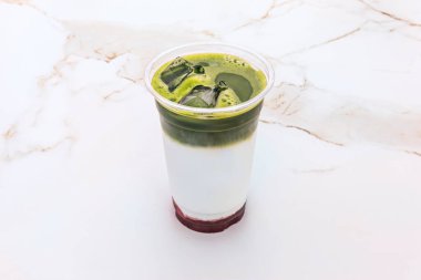 Tatların ve renklerin ahengi: kibrit yeşili, çayın altın kahverengisi ve çift bardaktaki lattenin yumuşak bej rengi arasındaki tezat