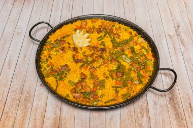 Kırmızı şaraplı ördek paella, leziz et parçaları ve harika pirinçler sergileniyor.