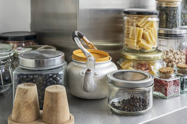 Altın sarısından kırmızı biberin koyu kırmızısına kadar renkli baharat kavanozlarıyla dolu bir raf.