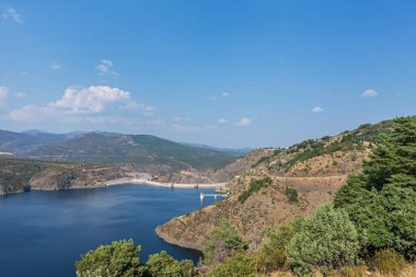 Barajın sonbahar manzarası, altın meşe ağaçları ve yemyeşil meşe ağaçları barajın yoğun maviliğini çerçeveliyor.