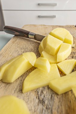 Julienne 'in organik çiğ patatesleri kırsal mutfak arka planına sahip bir akçaağaç tahtasında kesilmiş.