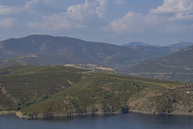 Yaz aylarında doğal kaya terasları ve dağ bitkileriyle çevrili bir rezervuarın panoramik manzarası