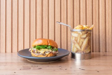 Pirzola ve Chuck karışımlı gurme burger, eritilmiş, dilimlenmiş domates ve taze marullu çörek.