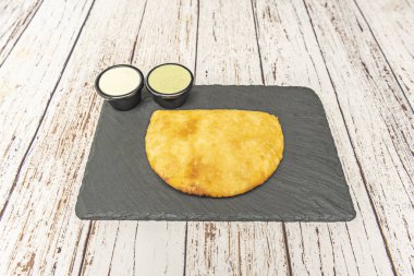 Şili çam böreği, haşlanmış yumurta ve zeytin geleneksel kişniş, sarımsak ve yeşil biberle servis edilir.