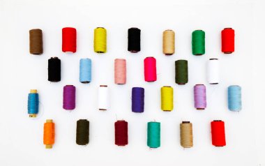 Beyaz arkaplanda çok renkli iplik bobinleri.