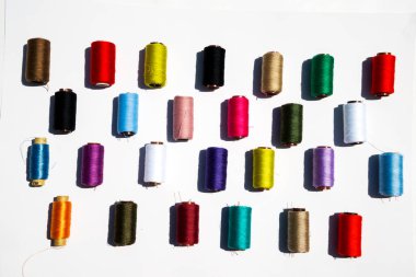 Beyaz arkaplanda çok renkli iplik bobinleri.