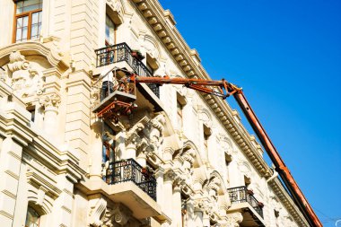 İnşaat işçileri geri yükleme için vinç araç kova ve bina cephe onarım.