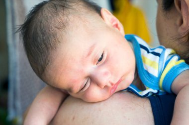 Bebek küçük mavi gözlü çocuk annesinin kollarında teselli için