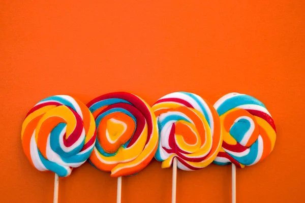 Bunte Spirale Lutscher Bonbons Auf Stock Auf Orangefarbenem Hintergrund — Stockfoto