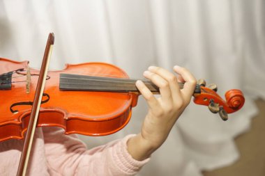 Sahnede bir melodi çalarken keman çalan mutlu, koyu tenli küçük kızın portresi.