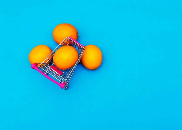 Πορτοκάλια Ένα Σιδερένιο Καροτσάκι Πάνω Μπλε Φόντο Επιχειρηματικές Και Υγιεινές — Φωτογραφία Αρχείου