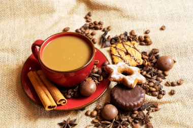 Kahverengi bir arka planda kahve ve kahve çekirdekli kırmızı fincan ve çay tabağı.