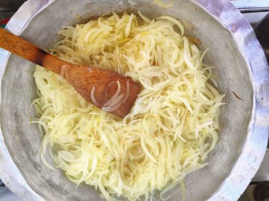 Soğanlar gaz sobasında alüminyum tavada kızartılır.