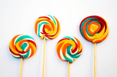 Çubukta renkli spiral lolipop şekeri. Turuncu bir arkaplanda.