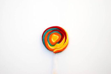 Çubukta renkli spiral lolipop şekeri. Turuncu bir arkaplanda.