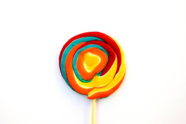 Çubukta renkli spiral lolipop şekeri. Turuncu bir arkaplanda.
