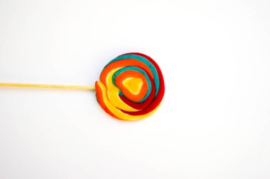 Çubukta renkli spiral lolipop şekeri. Turuncu bir arkaplanda.