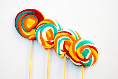 Çubukta renkli spiral lolipop şekeri. Turuncu bir arkaplanda.