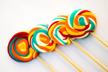 Çubukta renkli spiral lolipop şekeri. Turuncu bir arkaplanda.
