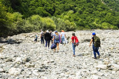 Azerbaycan, Shemakha. 20 Ağustos 2019: Bir grup turist nehir taşlarında yürüyor