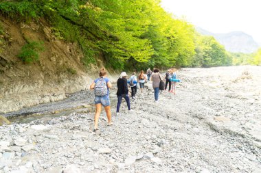 Azerbaycan, Shemakha. 20 Ağustos 2019: Bir grup turist nehir taşlarında yürüyor