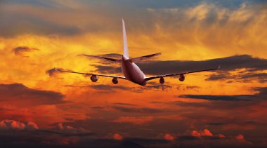 Airplane flying above dramatic clouds during sunset,sunrise