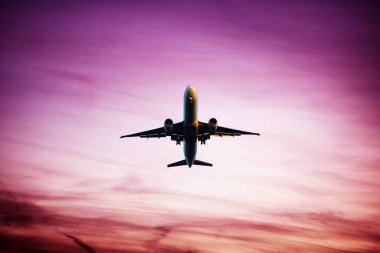 Airplane flying above dramatic clouds during sunset,sunrise