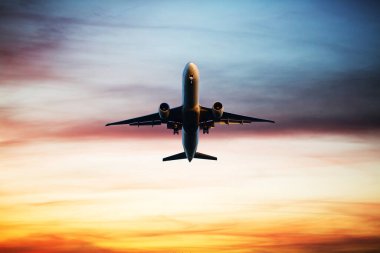 Airplane flying above dramatic clouds during sunset,sunrise