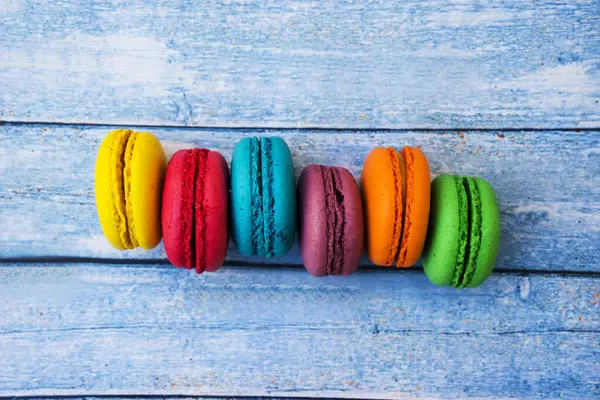 stock image Topshot of sweet and colourful french macaroons on blue wooden background.