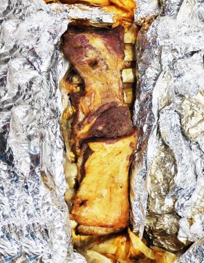 Profesyonel ızgara kuzu budu folyoda yatıyor.