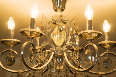 Odadaki tavandan sarkan parlak ampulleri olan kristal avize.