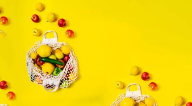 Sarı zemin üzerinde farklı sebzeler ve meyveler olan beyaz ip torbası. en üstteki görünüm