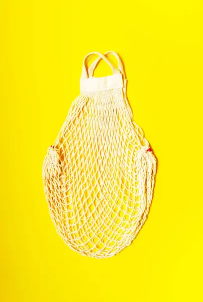 Empty White string bag on a yellow background. top view
