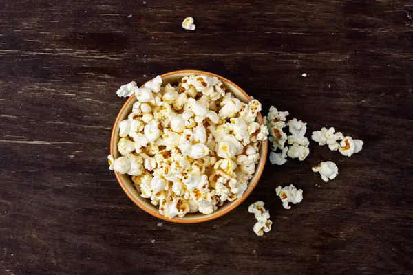 Kahverengi bir masada bir tabak patlamış mısır.