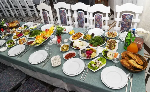 A festive and beautifully decorated wedding table. Decorated with flowers.various bottles of drinks, beautiful dishes, salads and sliced meat rolls.vegetable slicing.