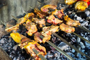 Izgarada bir sürü kebap var, dumanın içinde yakın plan kömürlerin üstünde..