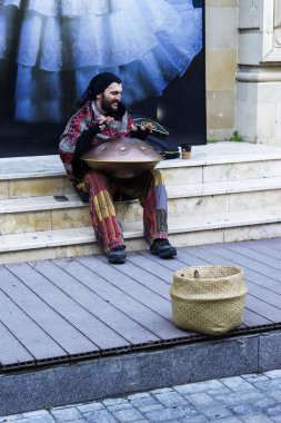 BAKU, AZERBAIJAN - 02 Aralık 2023: Rastalı ve sakallı genç bir adam perküsyon enstrümanı çalıyor.