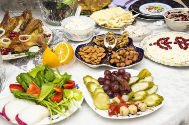 Masanın üzerinde farklı salatalar, sebzeler, meyveler var.