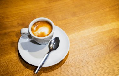 Kahverengi ahşap bir masada kahve fincanı ve çay tabağı.