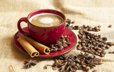 Red cup and saucer with coffee and coffee beans on a brown rag background clipart