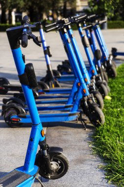 Otoparka park edilmiş kiralık mavi elektrikli scooterlar kullanıma hazır. Çevreyi kirletmeden etrafta dolaşmanızı sağlayan çok tanıdık bir araç. Çevre dostu ulaşım.
