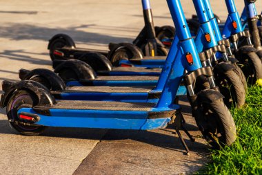 Otoparka park edilmiş kiralık mavi elektrikli scooterlar kullanıma hazır. Çevreyi kirletmeden etrafta dolaşmanızı sağlayan çok tanıdık bir araç. Çevre dostu ulaşım.