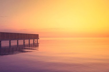 Pier in the sea mist at golden sunrise clipart