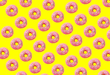 Sarı pastel arka planda pembe kaplı çörek deseni. Yaratıcı kavram