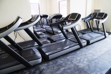 Modern bir spor salonu iç ekipmanları ile. Akşam arka plan ışığı içinde fitness kardiyo egzersizi için koşu bandı sıra ile fitness kulübü. Sağlıklı yaşam konsepti