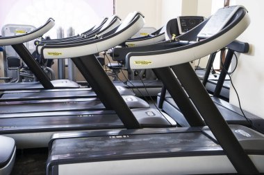 Modern bir spor salonu iç ekipmanları ile. Akşam arka plan ışığı içinde fitness kardiyo egzersizi için koşu bandı sıra ile fitness kulübü. Sağlıklı yaşam konsepti